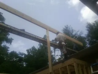 Carpenter setting a ridge beam over a new addition frame — Ice Dam Removal by Roofing Brothers in Davis City