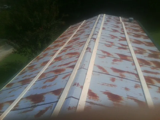 Rusted metal roof panels with new wood purlins before replacement — Storm Damage Roof Repair in Davis City by Roofing Brothers