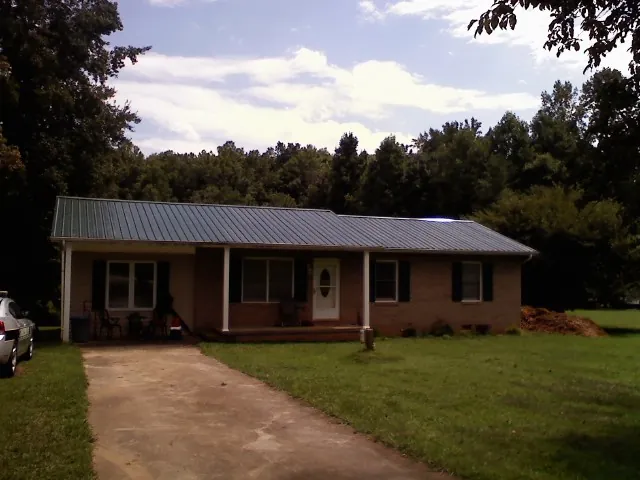 Dark green metal roof on a brick ranch with a covered porch in Davis City