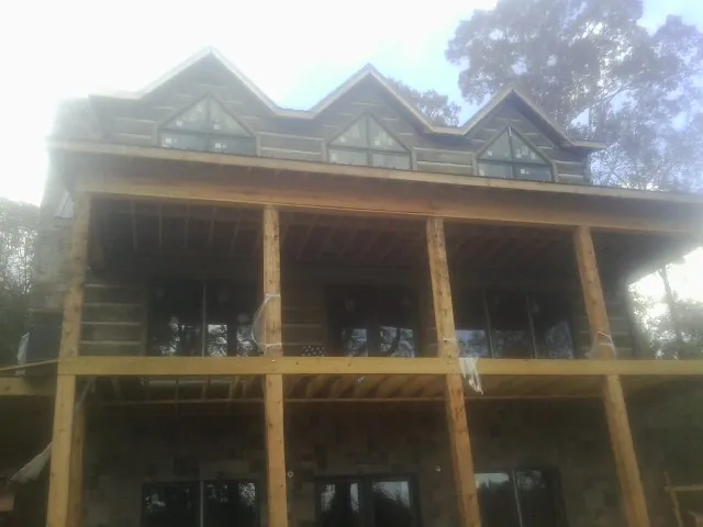 Dormers and porch framing on a large log home under construction — Roof Coating work by our crew in Davis City