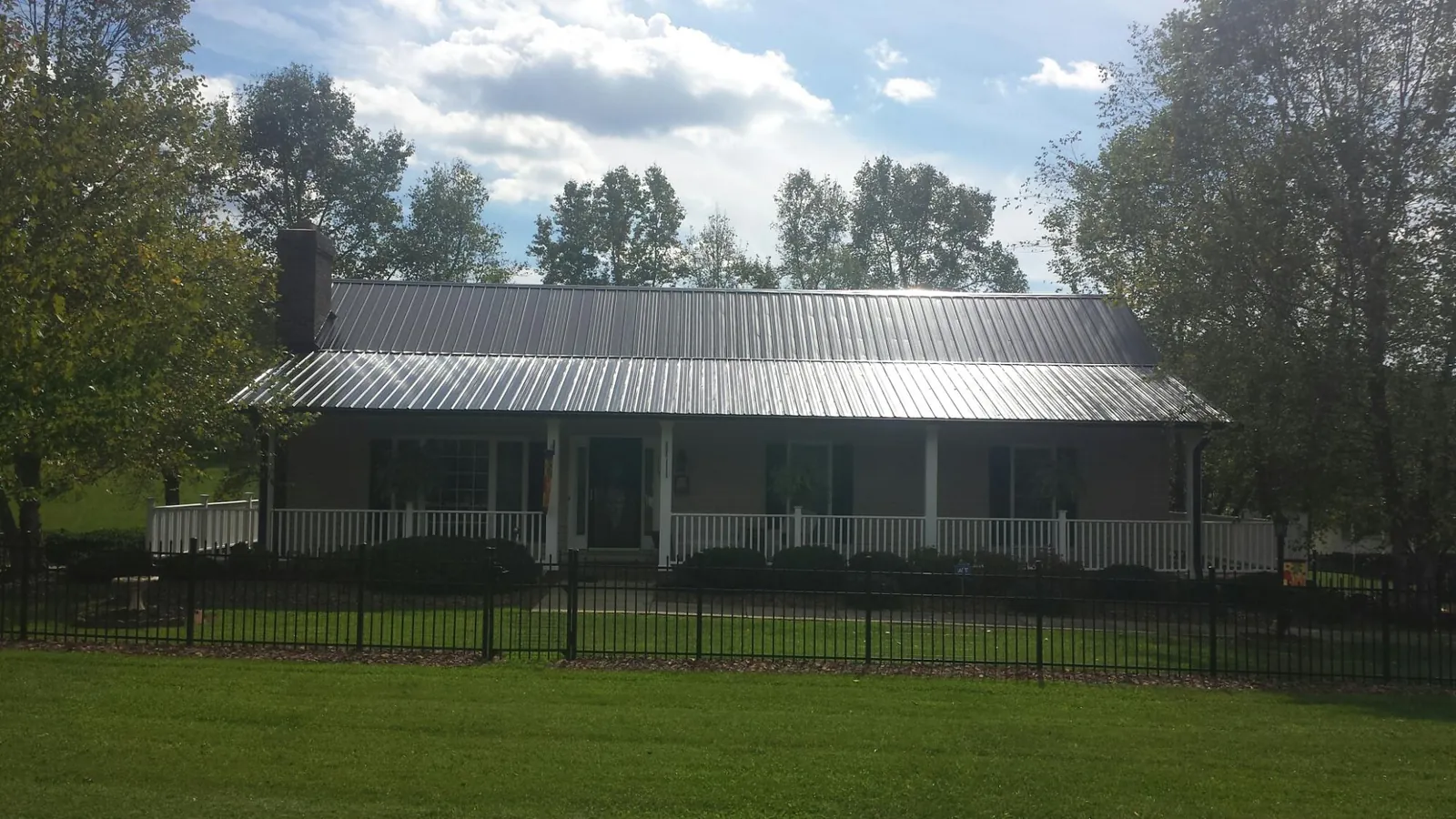 Gray metal roof on a brick ranch with a full width front porch — Gutter Guard Installation work by our crew in Davis City