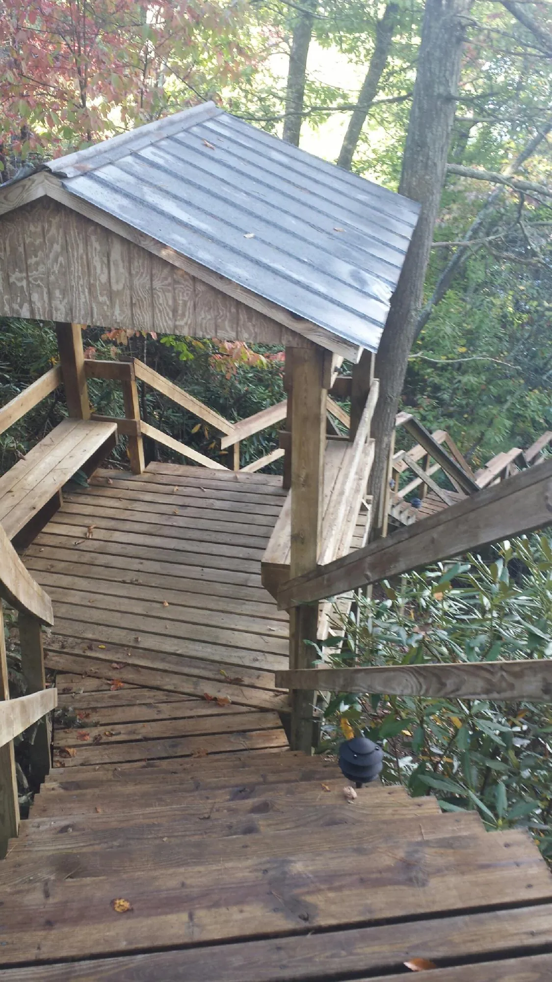 Metal roofed shelter over wooden steps on a wooded walkway — Skylight Repair & Installation work by our crew in Davis City