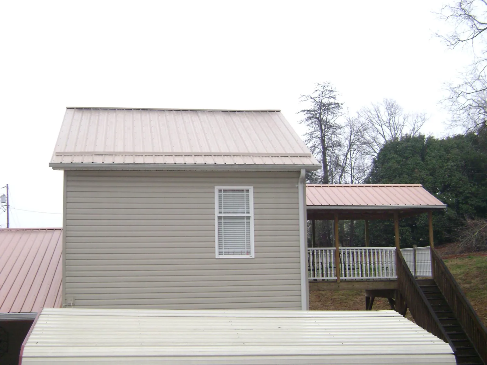 Tan metal roofs on a two story addition and attached porch, from a Roof Replacement job in Davis City
