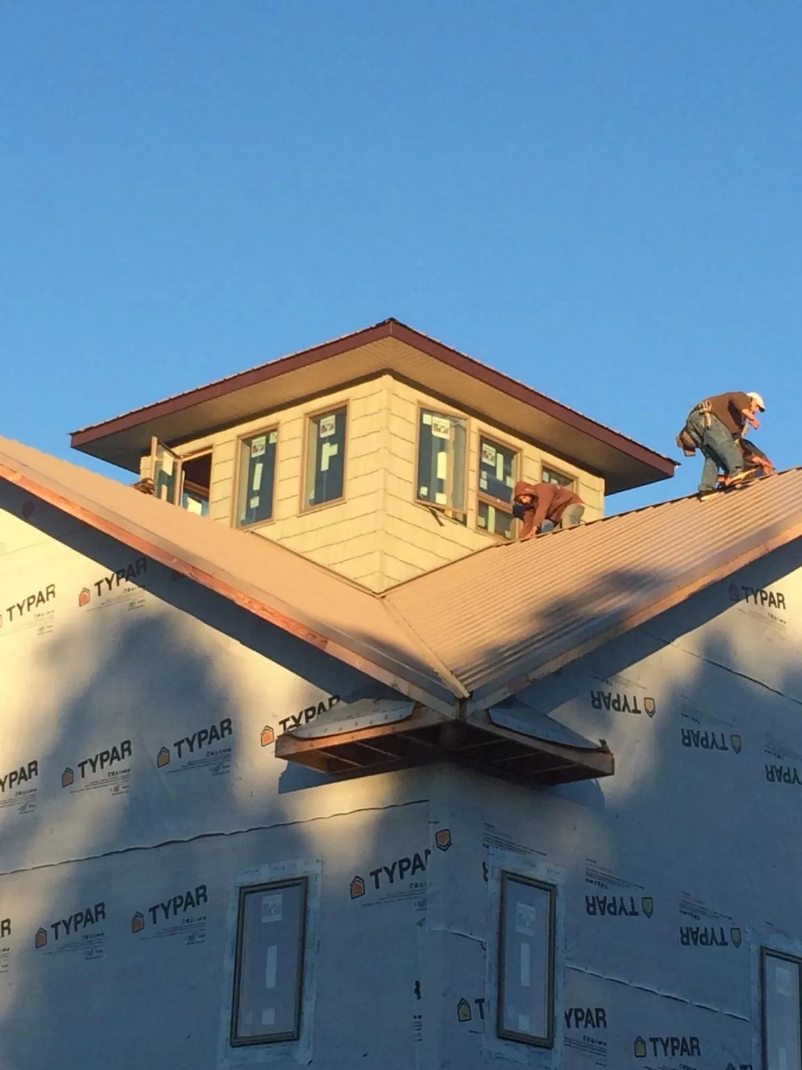 Roofers working around a rooftop cupola on a new metal roof at sunset — Roof Waterproofing in Davis City by Roofing Brothers